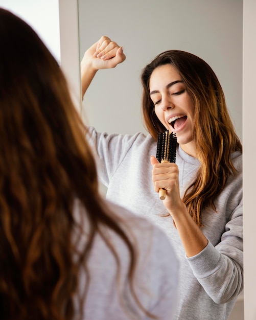 自宅でヘアブラシに歌う女性の正面図