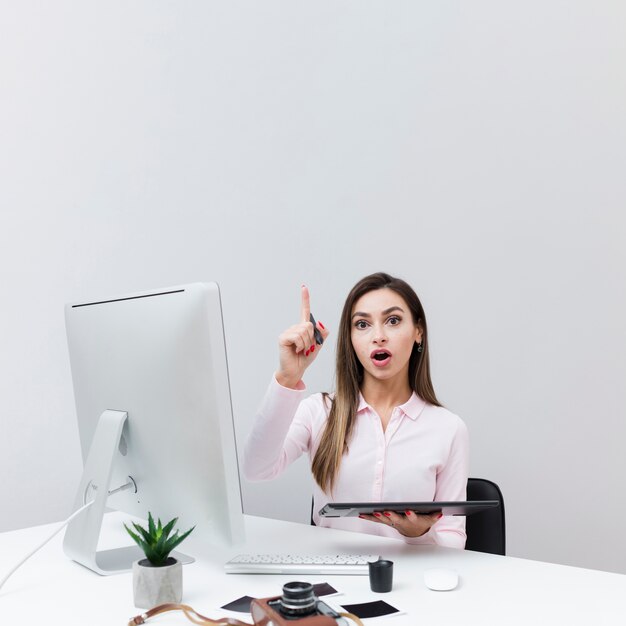 Front view of woman sitting at desk and having an idea