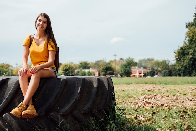 Foto gratuita vista frontale della donna che si siede sulla ruota del trattore