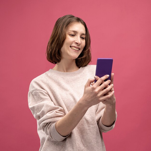 Front view of woman smiling and looking at smartphone