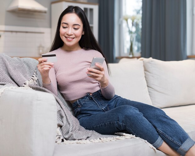 Front view of woman on sofa ordering online using credit card