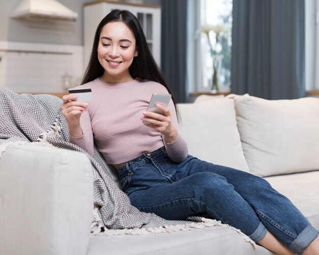 クレジットカードを使用してオンラインで注文するソファの上の女性の正面図