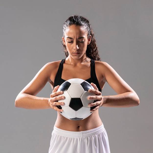 Front view woman in sportswear holding ball