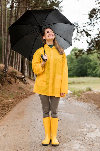 Женщина вид спереди, стоя в лесу, держа зонтик