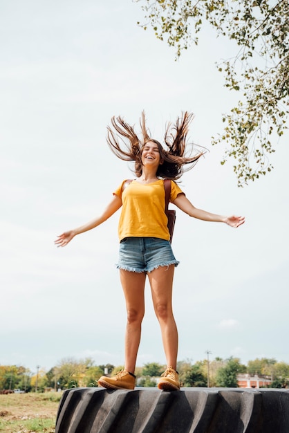 Free photo front view of woman standing on a tractor wheel