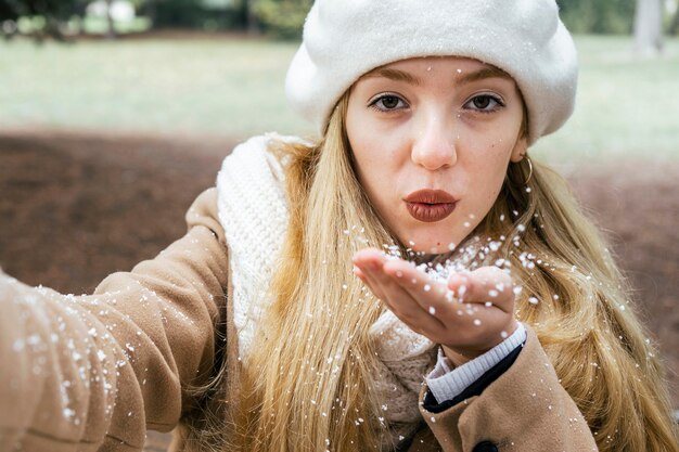 Front view of woman taking selfie in the park during winter with snow