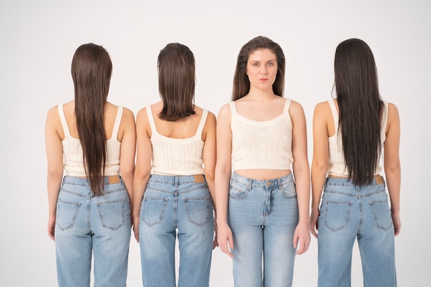 Front view of woman in tank top and jeans standing next to other women with turned backs