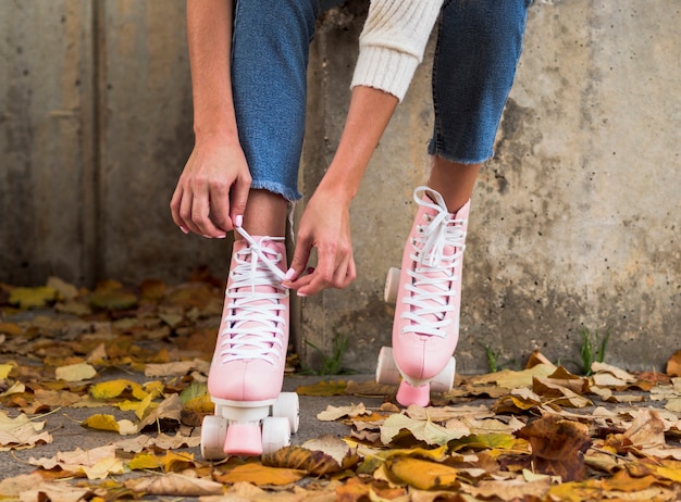 Вид спереди женщины, связывая шнурки на роликовых коньках с листьями