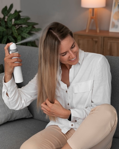 Front view woman using dry shampoo at home