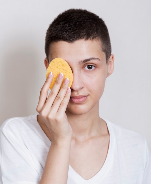 Front view woman using a face sponge 