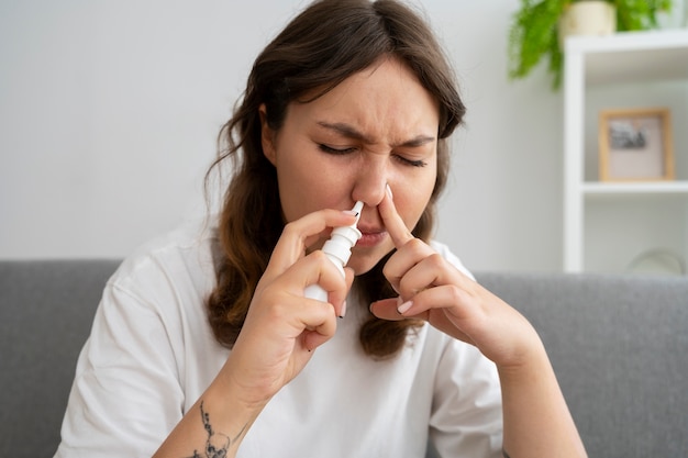 front view woman using nasal spray
