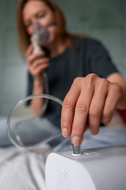 Free photo front view woman using nebulizer at home