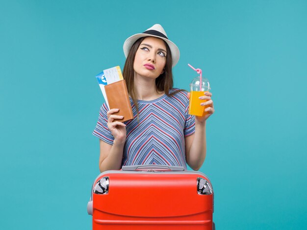 Front view woman in vacation holding fresh juice and tickets on a blue background trip journey voyage vacation sea summer