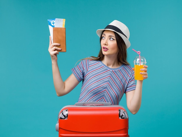 Front view woman in vacation holding her juice and tickets on light blue background trip summer sea journey voyage vacation