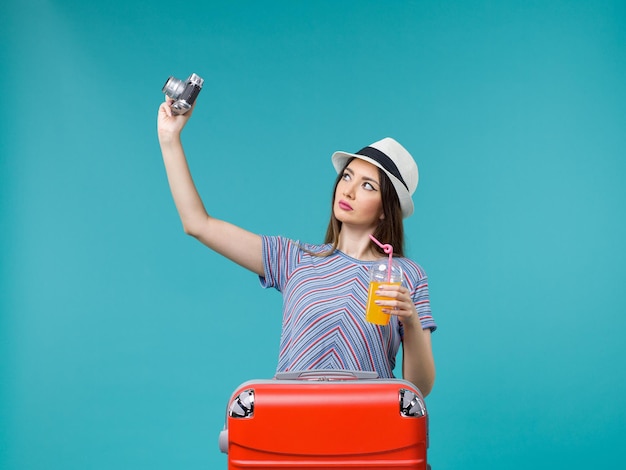 Front view woman in vacation holding juice and camera on blue background voyage summer journey vacation sea trip