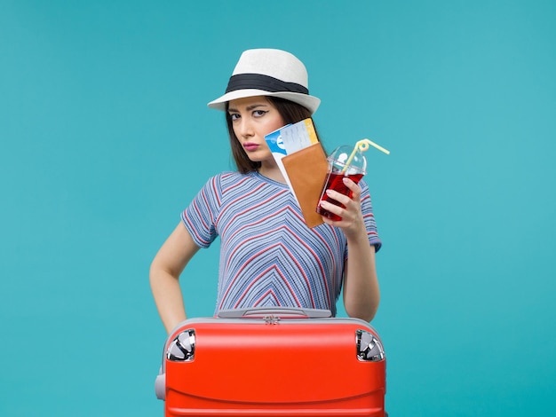 Front view woman in vacation holding juice with tickets on a blue background female sea summer voyage plane journey