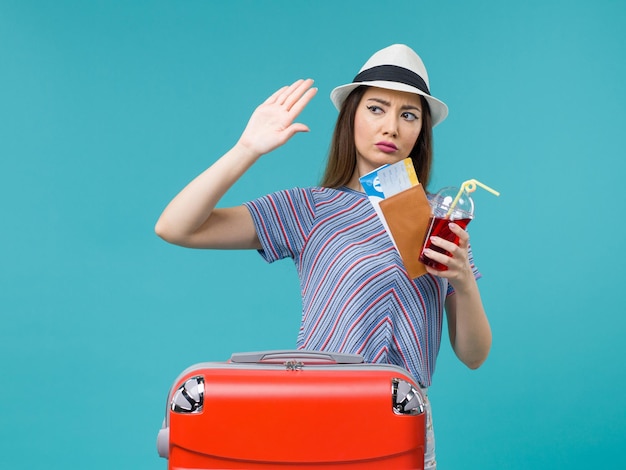 Front view woman in vacation holding juice with tickets on blue background voyage female sea summer plane journey