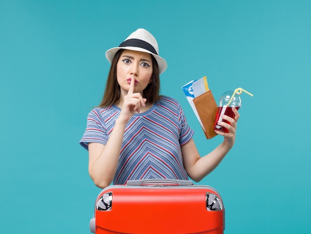 Front view woman in vacation holding juice with tickets on blue background voyage journey female sea plane summer