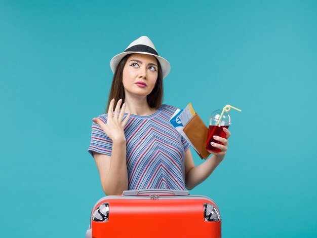 青い背景の航海の旅の女性の水上飛行機の夏のチケットとジュースを保持している休暇中の正面図の女性