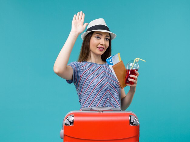 青い背景の航海の旅の女性の海の夏の飛行機のチケットとジュースを保持している休暇中の女性