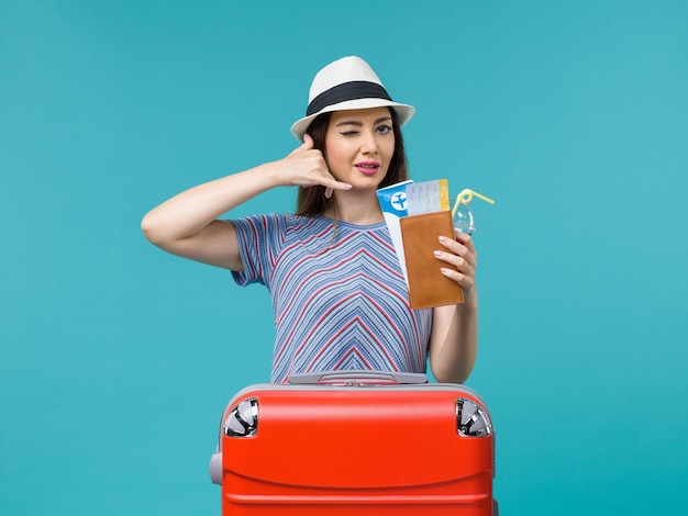 Вид спереди женщина в отпуске, держащая билеты на синем фоне, путешествие, путешествие, женский гидросамолет, лето