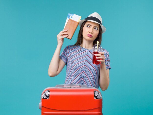 Вид спереди женщина в отпуске, держащая билеты и сок на синем фоне, путешествие, путешествие, женский гидросамолет, лето