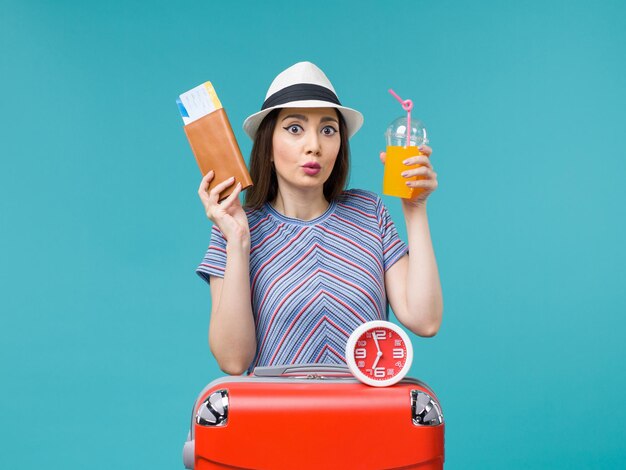 Front view woman in vacation holding tickets and juice on blue desk voyage vacation sea trip journey female