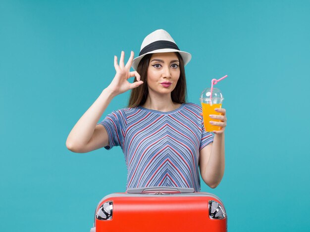 Front view woman in vacation with her red bag holding her juice on blue background trip journey voyage vacation female