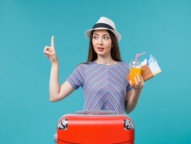 Front view woman in vacation with her red bag holding tickets and juice on blue background journey trip voyage vacation female