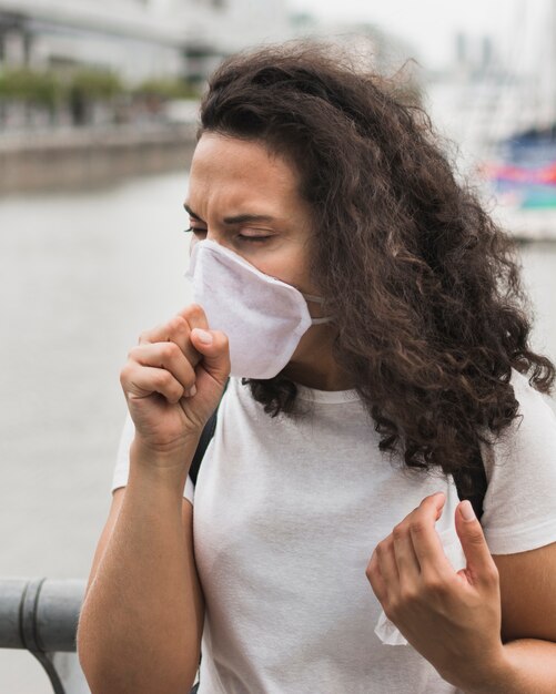 Front view woman wearing medical mask while coughing