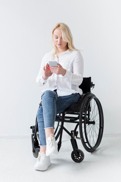 Вид спереди женщины в инвалидной коляске, держа смартфон
