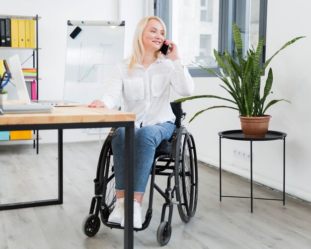 Front view of woman in wheelchair talking on phone at work