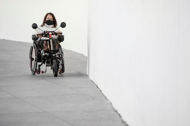 Free photo front view of woman in a wheelchair with mask and copy space