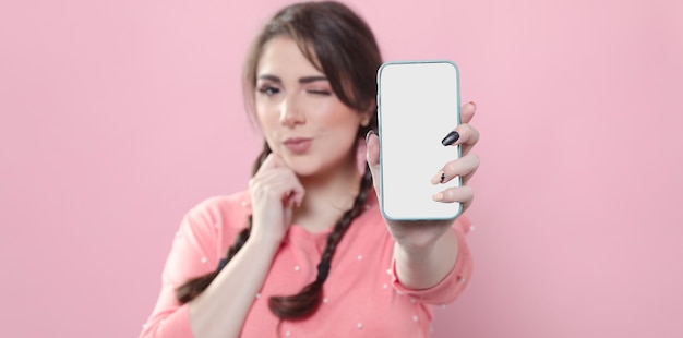 Front view of woman winking and holding up smartphone