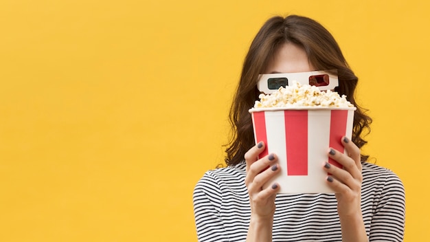 Женщина вид спереди в 3d очках закрыла лицо ведром с попкорном