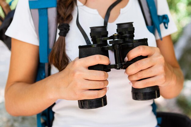 Front view of woman with backpack and binoculars outdoors