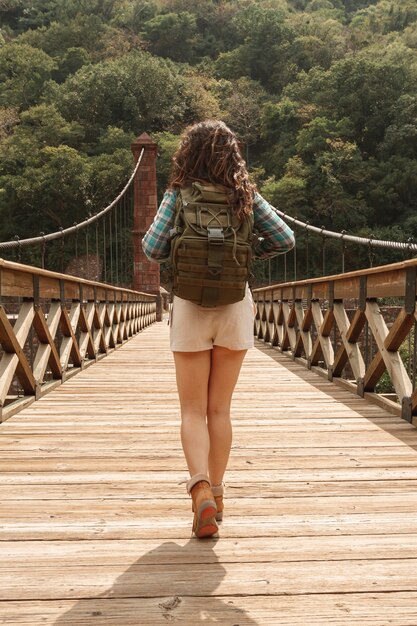 Front view woman with backpack on bridge