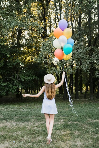 Front view woman with balloons walking