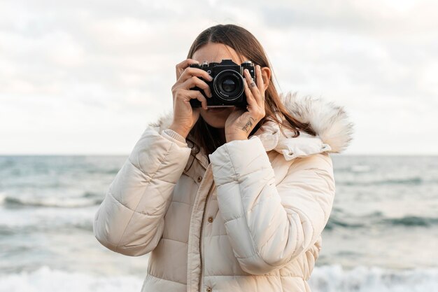 Front view of woman with camera at the beach