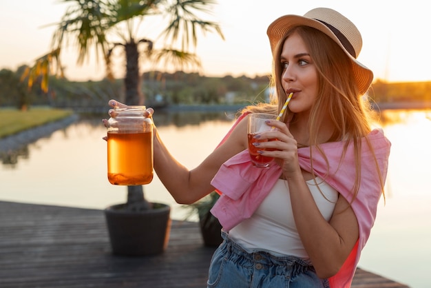 Free photo front view woman with delicious kombucha outdoors