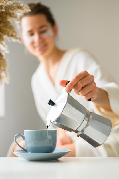 Front view of woman with eye patches pouring coffee