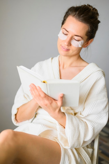 Front view of woman with eye patches reading a book