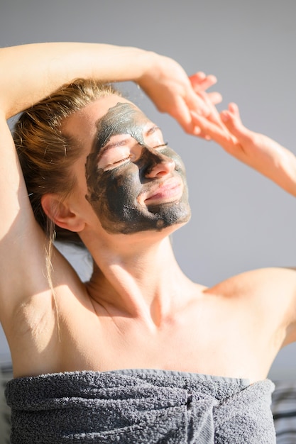 自宅で太陽を浴びてフェイスマスクを持つ女性の正面図