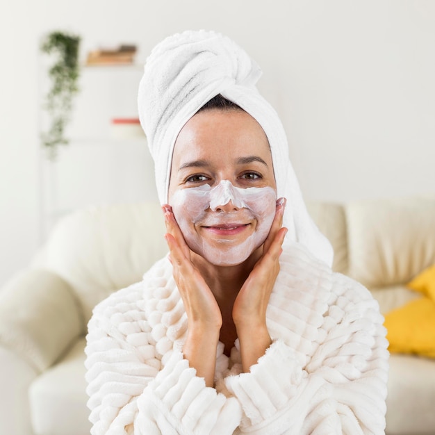 Front view woman with facial mask wearing bathrobe