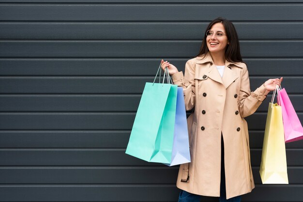 Front view of woman with glasses holding lots of shopping bags with copy space