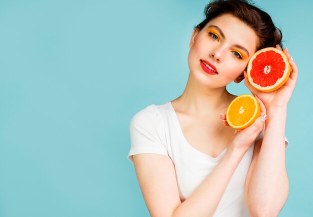 Front view of woman with grapefruit and orange