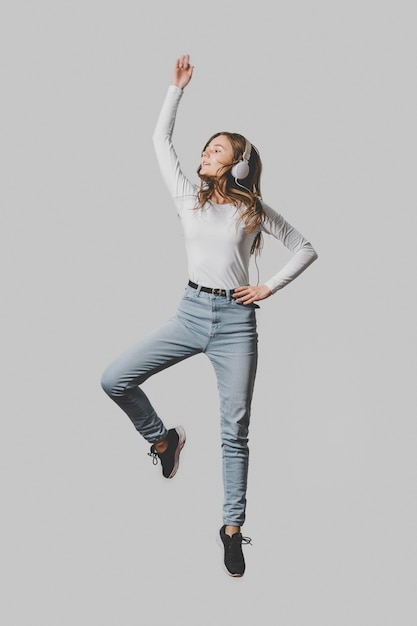 Front view of woman with headphones jumping in the air