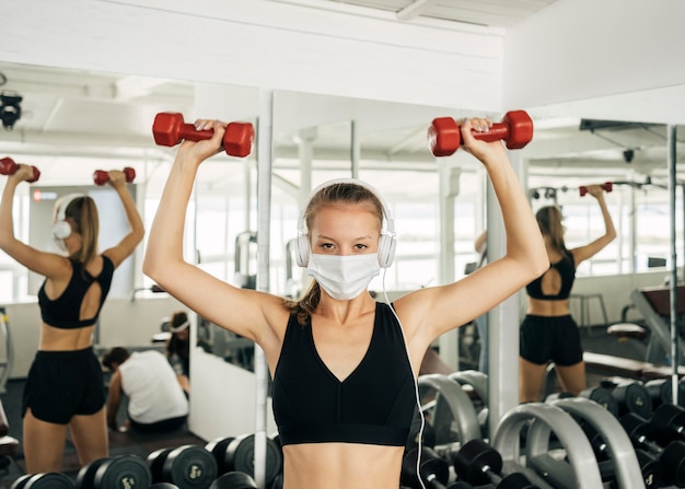 Front view of woman with headphones and medical working out at the gym