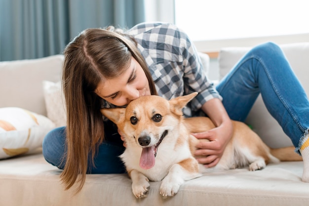 ソファの上の彼女のかわいい犬を持つ女性の正面図