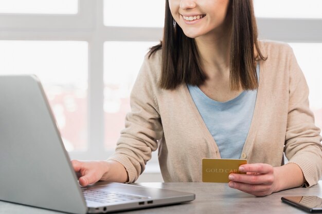 ノートパソコンとクレジットカードを持つ女性の正面図